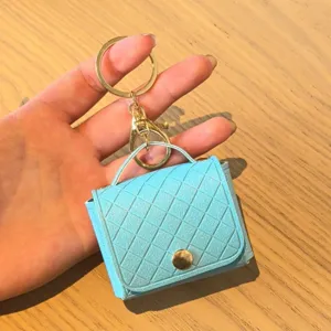 Lichtblauwe gewatteerde PU mini tas sleutelhanger en oordopjeshoesje met gouden hardware.