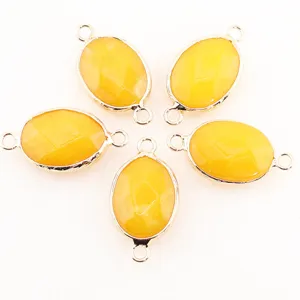 Vue détaillée de pendentifs connecteurs ovales en cristal et pierre naturelle avec sertissage doré.
