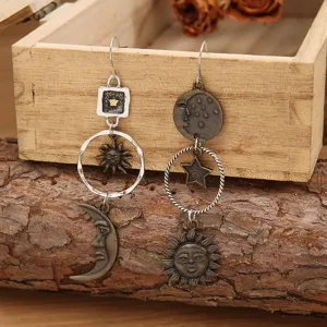 Vue détaillée de boucles d'oreilles pendantes asymétriques soleil lune et étoile.