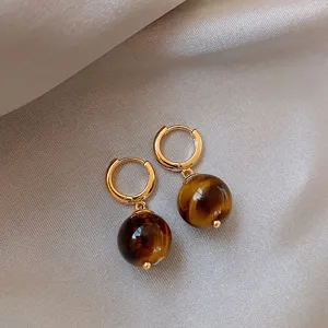Detailed shot of French vintage natural tiger's eye hoop earrings, chic light luxury drop style.