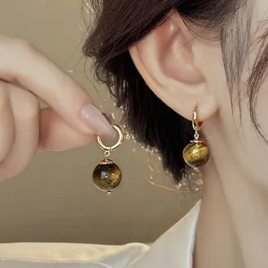 Detail shot of French retro natural tiger eye gemstone hoop earrings with gold metal finish.