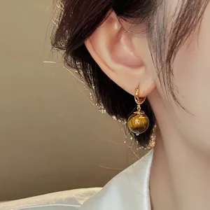 Detailed close-up of French vintage gold hoop earrings with natural tiger's eye stone charm.