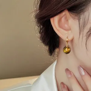 Close-up detail of vintage style gold hoop earrings with natural tiger eye stone beads elegant.
