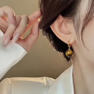 Close-up detail of french vintage natural tiger eye stone hoop earrings elegant gold jewelry.