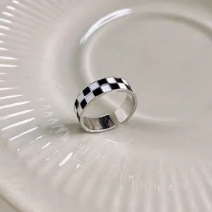 Close-up detail of a trendy retro black and white checkerboard open ring, stylish design.