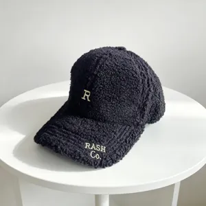 Gros plan sur la casquette de baseball en teddy noir avec broderie, texture douce.