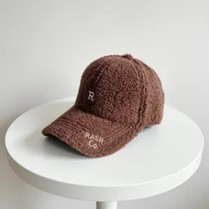 Vue détaillée de la casquette de baseball marron en sherpa duveteux avec broderie de lettres.