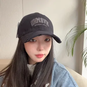 Detail view of the distressed black baseball cap worn by a model, featuring curved embroidery.
