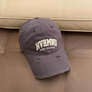 Detail shot of charcoal grey distressed baseball cap with embroidered lettering and worn-out brim.