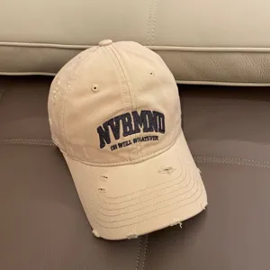 Distressed beige baseball cap with vintage embroidered letters, soft top casual hat detail.