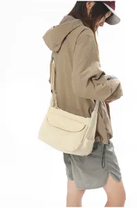 Detail view showing the casual canvas crossbody bag worn by a model in a clean studio setting.