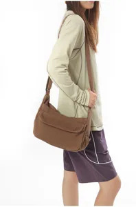 Detail view of the brown canvas shoulder bag, showing the flap pocket and wide strap texture.