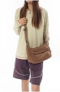 Close-up detail shot of a retro brown canvas shoulder crossbody bag worn by a model.