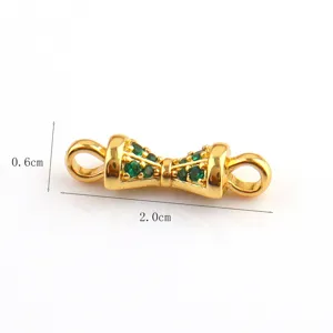 Detail view of golden bow jewelry connector with green stones, DIY craft accessory for bracelets.