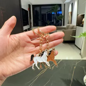 Vue détaillée du charmant porte-clés double cheval en alliage avec des chaînes dorées.