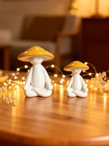 Close-up detail of cute meditating mushroom figurines with warm fairy lights in cozy room decor.