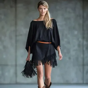 Detailed view of the elegant black fringe dress outfit in outdoor concrete wall setting.