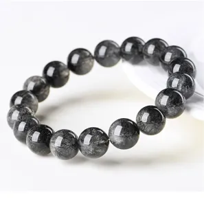 Close-up detail of natural black rutilated quartz round bead bracelet, highly polished shiny surface.