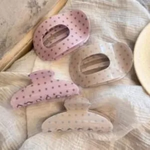 Vue détaillée de jolies pinces à cheveux à pois roses et beiges, accessoires chics et mignons.