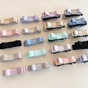 Vue détaillée de pinces à cheveux assorties en satin nœud papillon aux douces couleurs pastel.