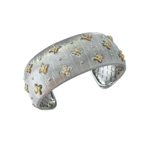 Bracciale rigido largo spazzolato stile oro 18k con scintillanti fiori di diamanti.