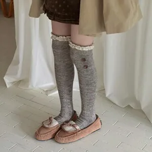 Calze grigie al ginocchio in maglia con delicato bordo in pizzo e bottoni laterali per outfit.