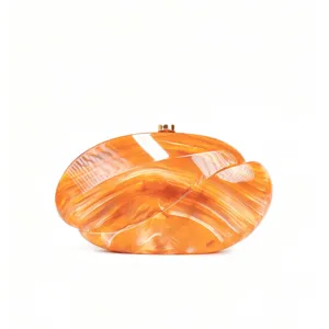 Close-up detail of orange marbled acrylic clutch bag, showcasing glossy texture and metal clasp.