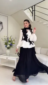 Detail view of elegant black and white floral blouse with pleated skirt set showcasing style.