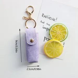 Mini portachiavi porta rossetto in denim viola con finiture dorate e chiusura a pressione.