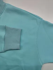 Light blue sweatshirt fabric detail showing ribbed cuff and collar seam close up view.