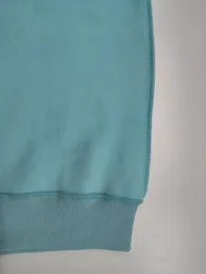 Detailed view of the light blue fleece sweatshirt hem, showing fine stitching and soft texture.
