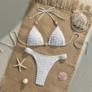 White textured bikini set with beaded halter top and matching bottoms for beach.