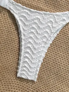 White textured bikini bottom detail view, featuring unique beaded wave fabric and lace-up sides.