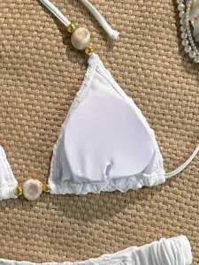 White textured beaded bikini top detail showcasing shell beads and golden metallic accents.
