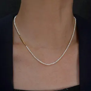 Gros plan detaille sur collier de perles delicat, accent barre dore, chaine clavicule chic.