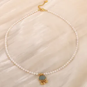 Gros plan détaillé d'un collier de perles d'eau douce avec pendentif cadenas jade or.