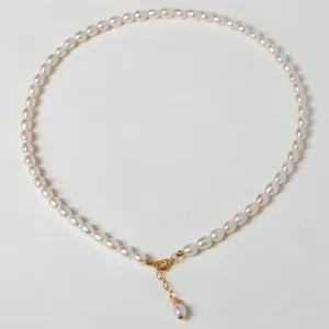 Gros plan détaillé d'un collier de perles d'eau douce délicat avec fermoir et chaîne de rallonge.