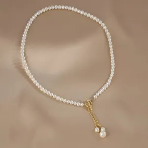 Détail de collier en perles d'eau douce avec perles rondes élégantes et fermoir T doré.