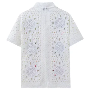 Detailed view of the white crochet knit fabric texture and floral pattern on the shirt.