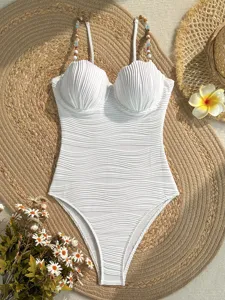 Primo piano sui dettagli del costume intero bianco con coppe a conchiglia e perline.