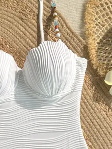 Elegante costume intero bianco con coppe a conchiglia, trama ondulata e belle perline.