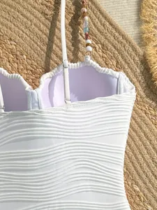 Dettaglio costume da bagno intero bianco testurizzato con spalline di perline