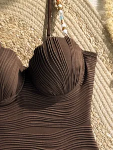 Dettaglio costume da bagno bikini intero marrone con coppe a conchiglia e perline.