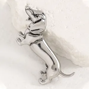 Gros plan d'une broche teckel argentée au design rétro avec une texture métallique raffinée.
