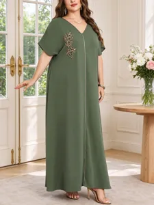 Detail shot of a women's green maxi dress featuring elegant gold leaf embroidery and V-neck.