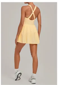 Back detail of yellow activewear tennis dress with cross straps and pleated skirt hem.