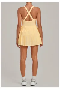 Back detail view of yellow activewear tennis dress with pleated skirt and cross straps.