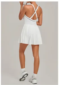 Detail shot of white athletic tennis dress featuring stylish cross back straps and pleated skirt.
