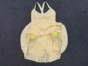 Detailed flat lay of yellow pleated athletic tennis dress, featuring built-in shorts and ball pockets.