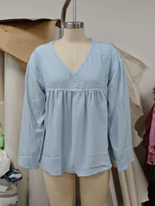 Hellblaue Langarmbluse mit V-Ausschnitt, zarter Spitzenborte und lässigem Pullover-Stil.
